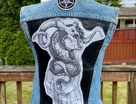 Ljusblå denimväst med svart ryggpanel, drakmotiv och rund symbol